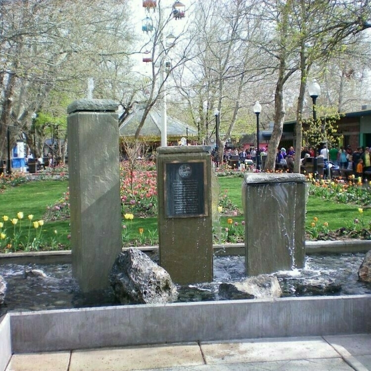 A picture of a small section of the Interactive Fountain and the gardens south of the Interactive Fountain. Sky Ride can be seen above the gardens as well as the trees the line the gardens area.