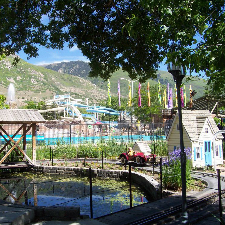 Speedway Jr. at Lagoon Amusement Park features small cars on a track. Each car can hold 2 kids. The ride is right next to Lagoon-A-Beach and has some fun features like a small house, a little pond, and some bird houses that the kids pass by while riding.