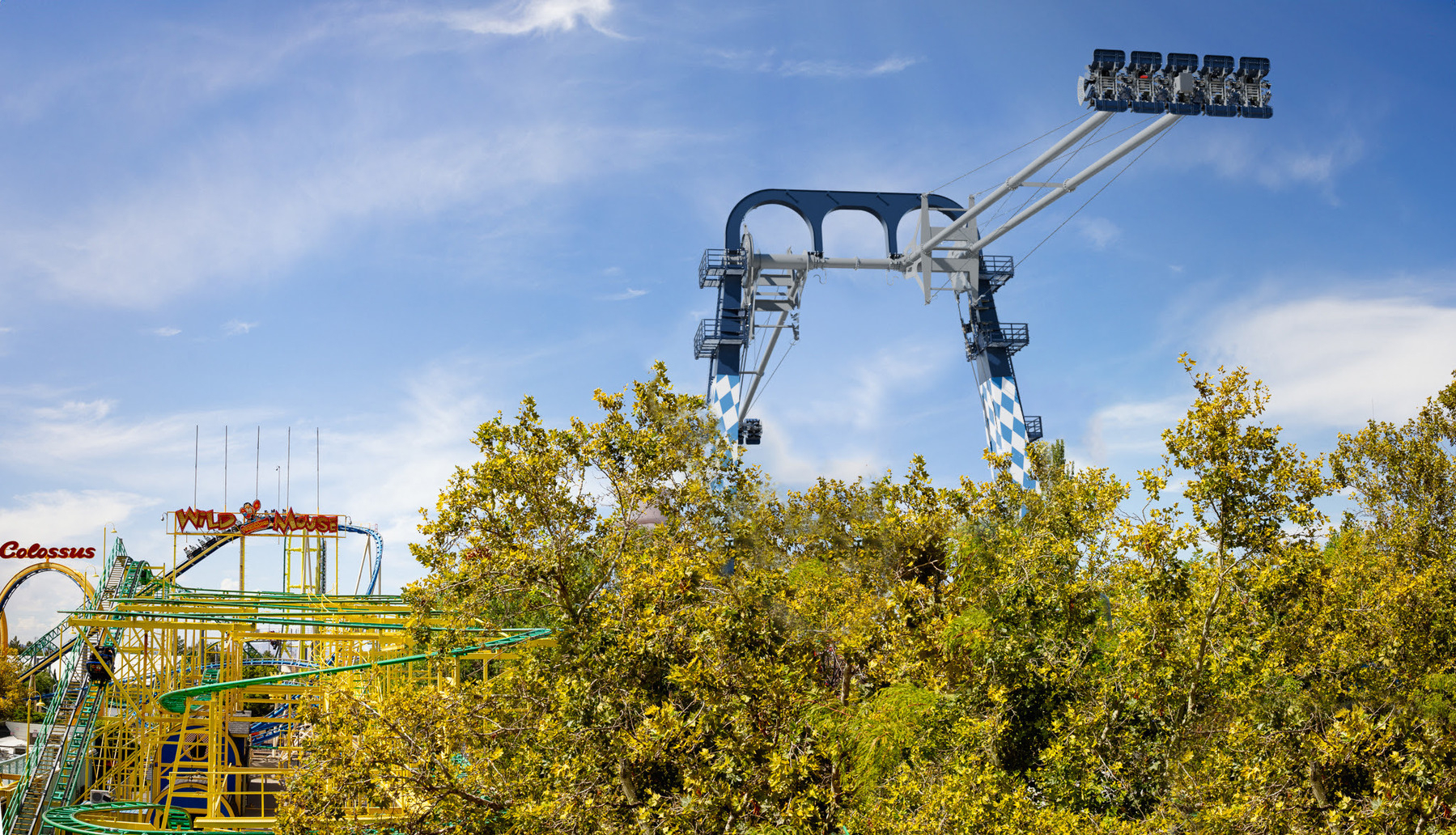 An amusement park ride towers over trees, with a large swing and a roller coaster visible.