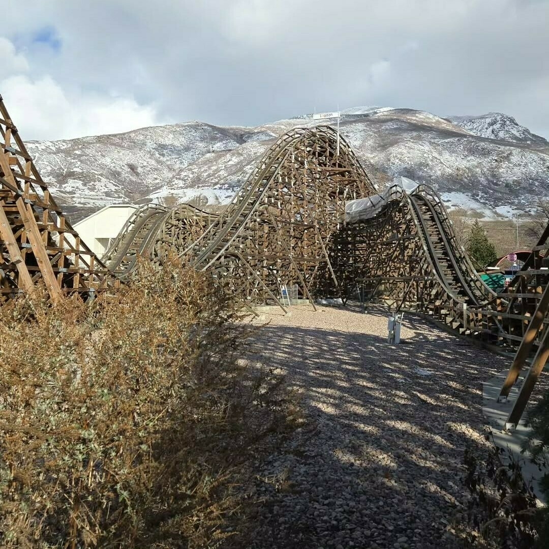 An image of Roller Coaster. The view is of the lift-hill and east turn taken from the walkway that goes through the middle of the coaster. There is snow on the mountains in the background.